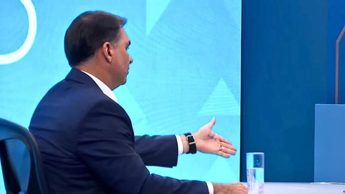 Candidato Flávio Bolsonaro exibe cola na mão e repete tática bizarra do pai na TV